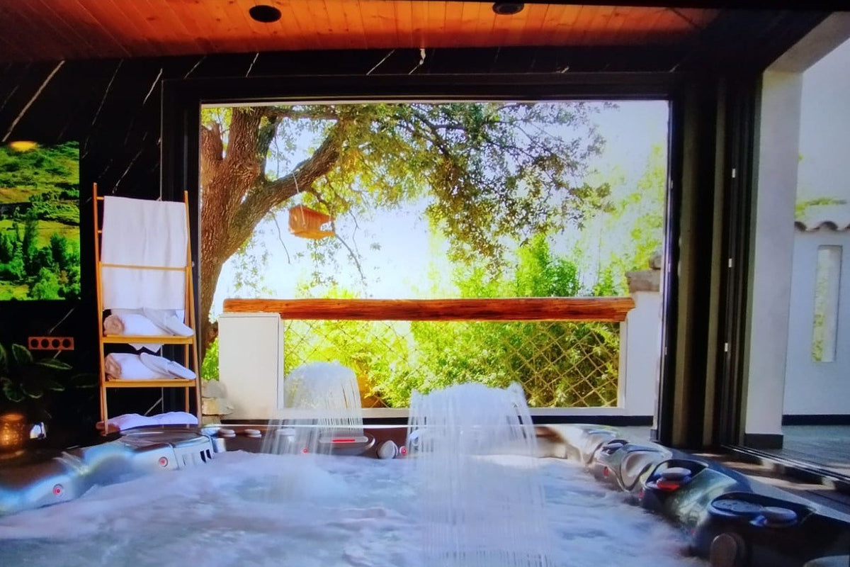 spa Caldera installé à l'intérieur, sous un plafond en bois, devant une baie vitrée grande ouverte sur le jardin